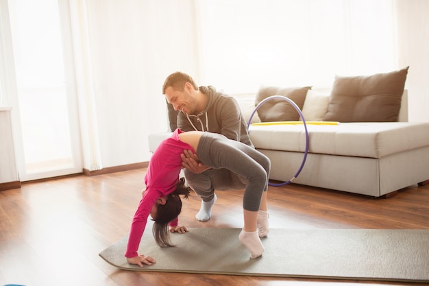 Pai e filha estão treinando em casa. Treino no apartamento. Esportes em casa em pose de ponte.