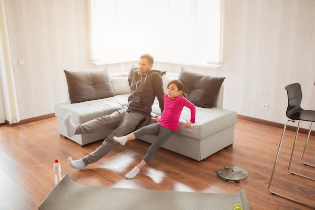 Foto pai e filha estão treinando em casa. treino no apartamento. esportes em casa.