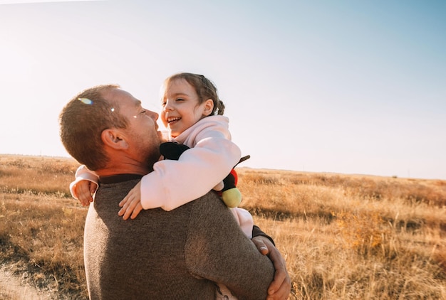 Pai e filha felizes a divertir-se a brincar ao ar livre sorrindo jovem pai e filha