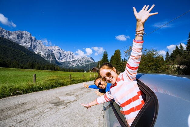 Pai e filha felizes e sorridentes, olhando pela janela do carro e as montanhas ao fundo. Dolomitas, Itália