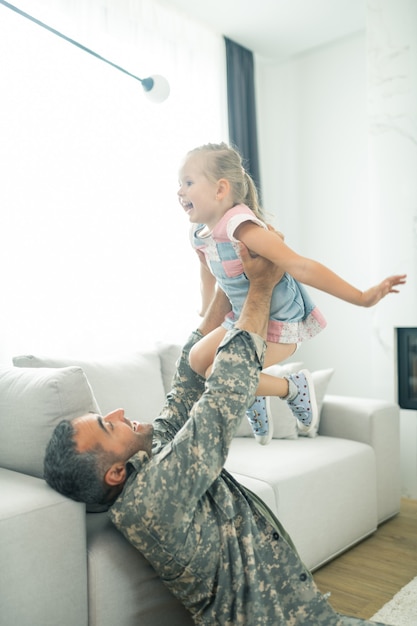 Pai e filha. homem voltando para casa após o serviço militar se sentindo alegre enquanto brincava com a filha