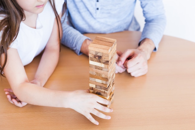 Pai e filha jogam em casa, custam uma torre de blocos, cubos, quebra-cabeças para o desenvolvimento do cérebro, inteligência mental