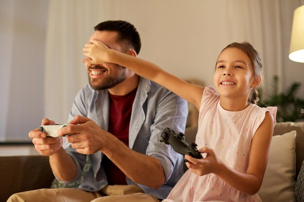 Foto pai e filha jogando videogame em casa