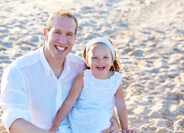 Pai e filha na areia da praia juntos