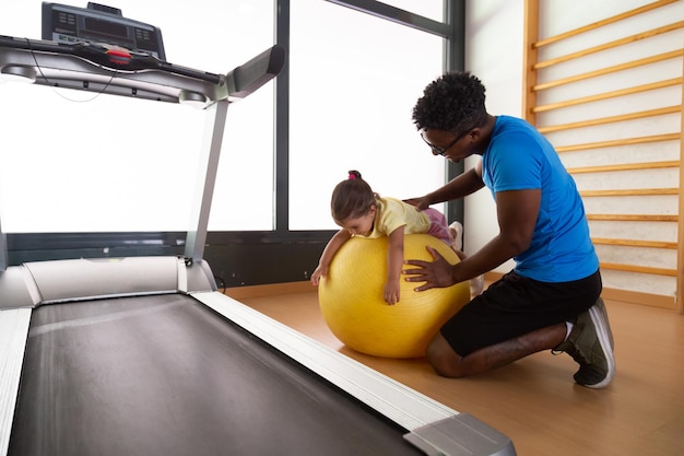 Pai e filha negros se exercitando com bola fit