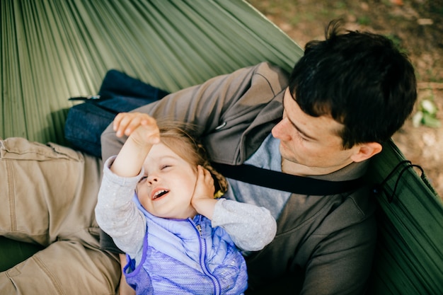 Pai e filha pequena relaxante na rede