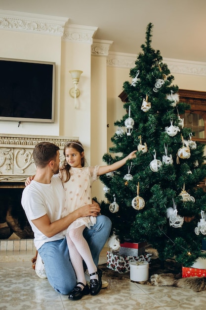 Pai e filha perto da árvore de natal