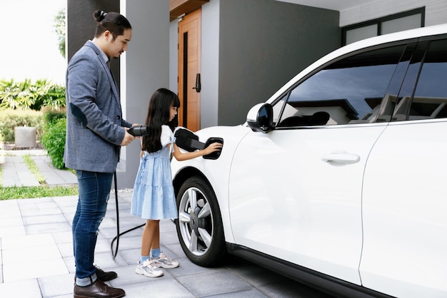 Pai e filha progressivos carregando carro EV da estação de carregamento em casa