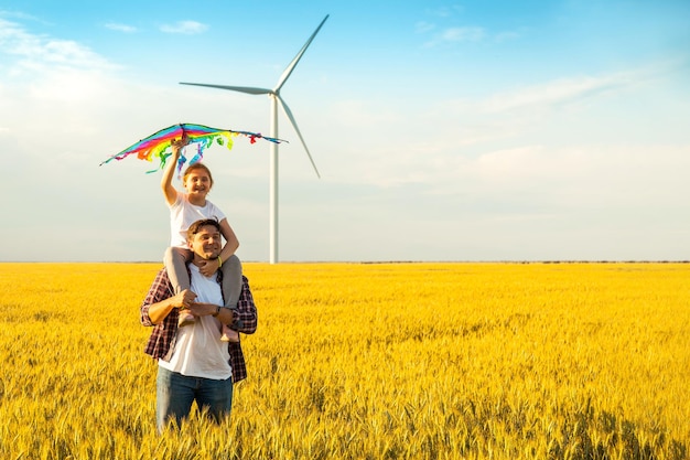 Pai e filha se divertindo brincando com pipa juntos no campo de trigo no dia de verão brilhante