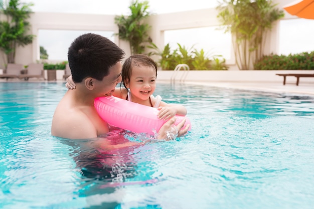 Pai e filha se divertindo na piscina. Férias de verão e conceito de férias