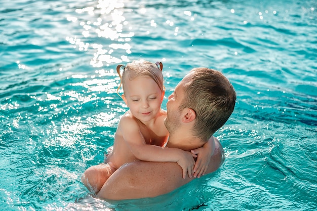 Pai e filha se divertindo nas férias de verão, jogando água na piscina ao ar livre