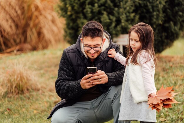 Foto pai e filha tirando uma selfie usando um telefone celular para acionar uma câmera dslr