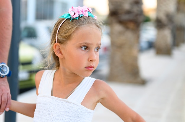 Pai e filha. uma menina bonitinha de seis anos segura a mão do pai enquanto caminhava pela rua da cidade