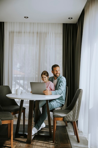 Pai e filha usando laptop juntos na sala