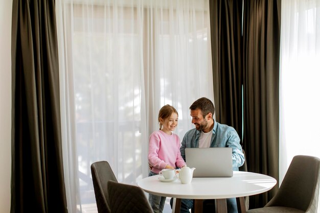 Pai e filha usando laptop juntos na sala