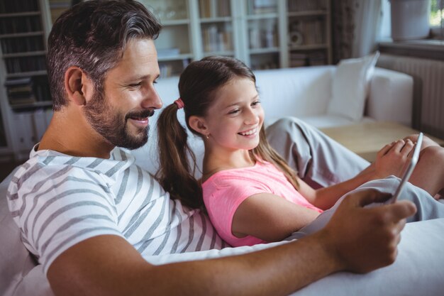 Pai e filha usando tablet digital na sala de estar