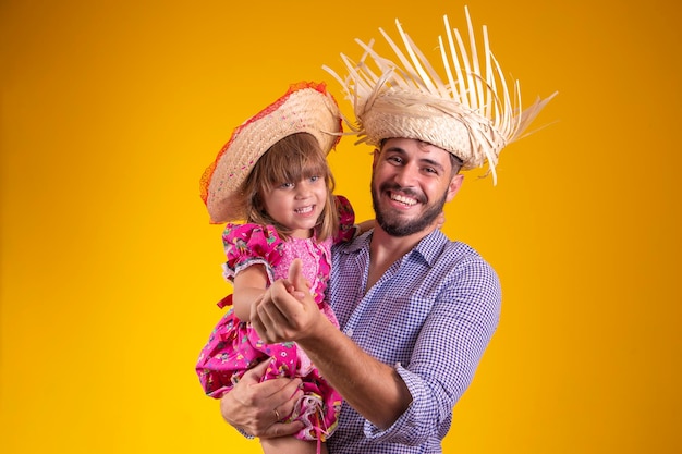 Pai e filha vestidos com roupas de festa junina dançando