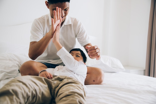 Pai e filho a brincar na cama em casa.