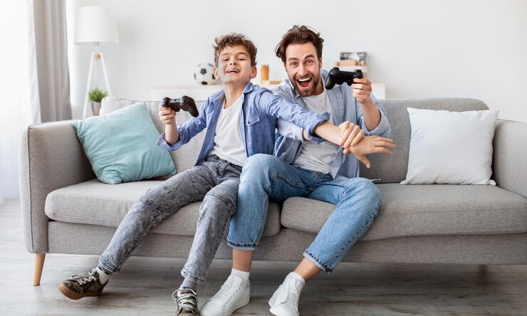 Foto pai e filho alegres com joysticks jogando videogames em casa menino distraindo pai com a mão