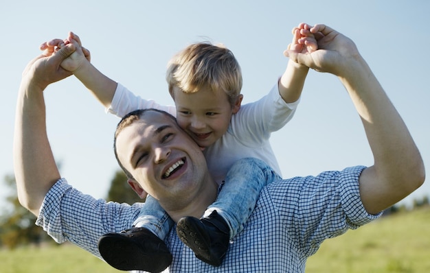 Pai e filho alegres contra o céu