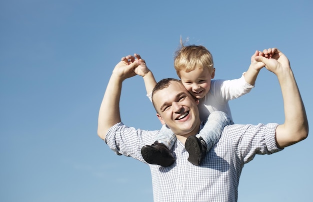 Pai e filho alegres contra o céu