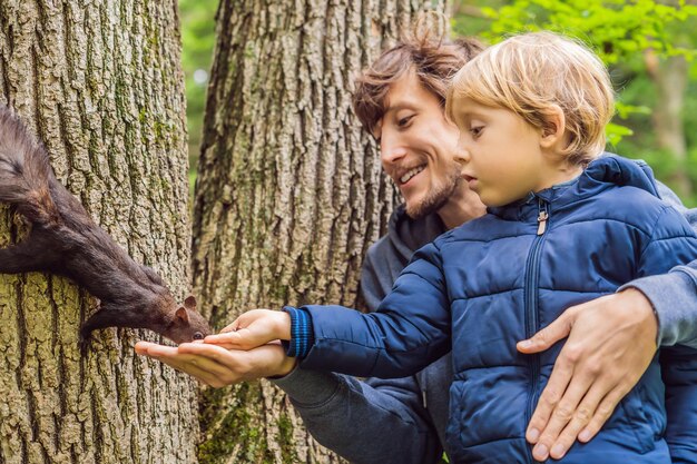 Pai e filho alimentam um esquilo no parque