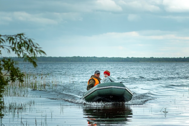 Pai e filho andam de barco a motor no lago.