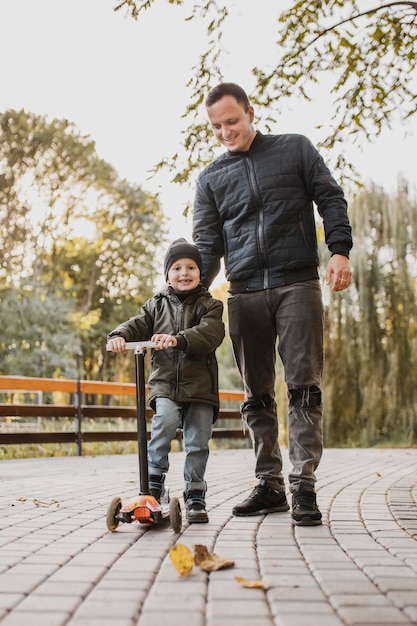 Pai e filho andando de scooter infantil