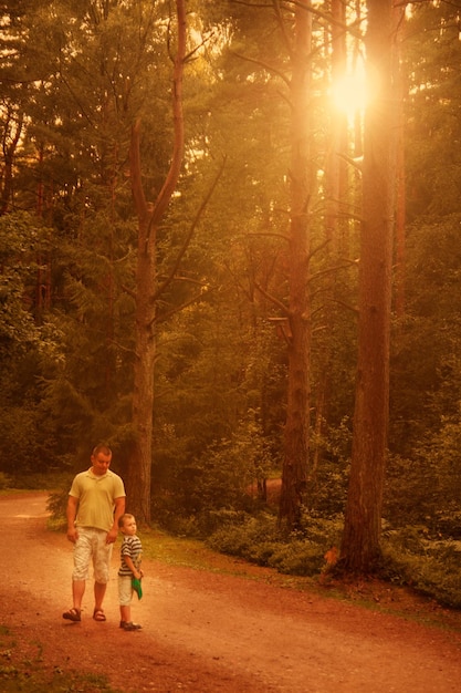 Pai e filho andando na floresta ao pôr do sol família feliz ao ar livre