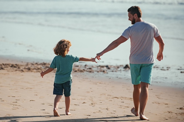 Pai e filho andando no mar pai e filho de mãos dadas e caminham juntos conceito de família amigável