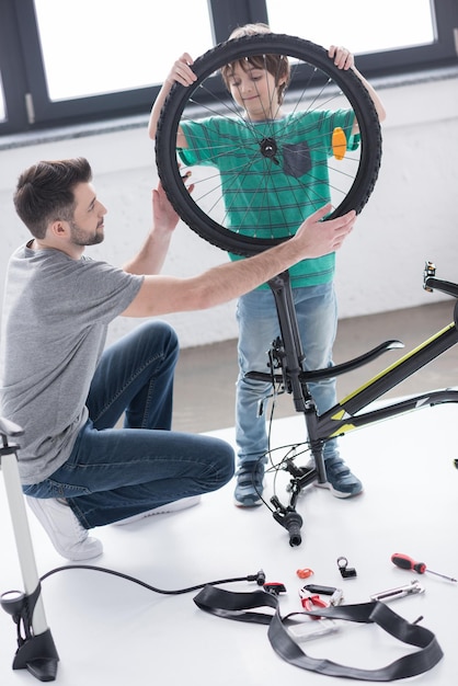 Foto pai e filho anexando uma roda de bicicleta juntos em branco
