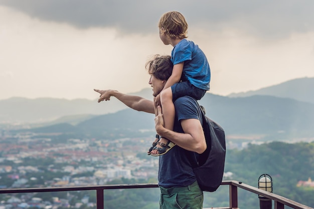 Pai e filho ao fundo da vista da cidade de Phuket da colina dos macacos