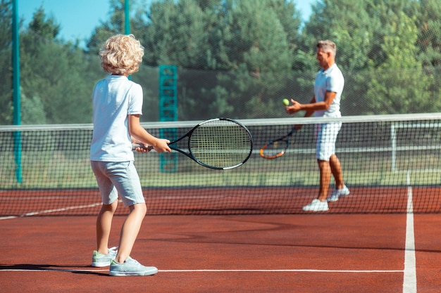 Pai e filho aproveitando o dia quente de verão jogando tênis lá fora