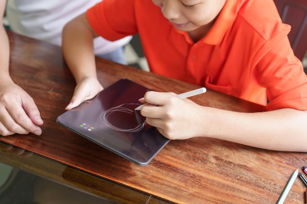 Pai e filho asiáticos usando tablet ensinando filho a desenhar xA jogando com tablet digital na mesa paternidade