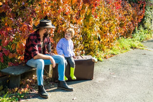 Pai e filho barbudo relaxando em um banco após uma caminhada na floresta, lazer familiar paternidade ...