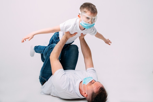 Pai e filho brincam durante a quarentena em máscaras médicas.