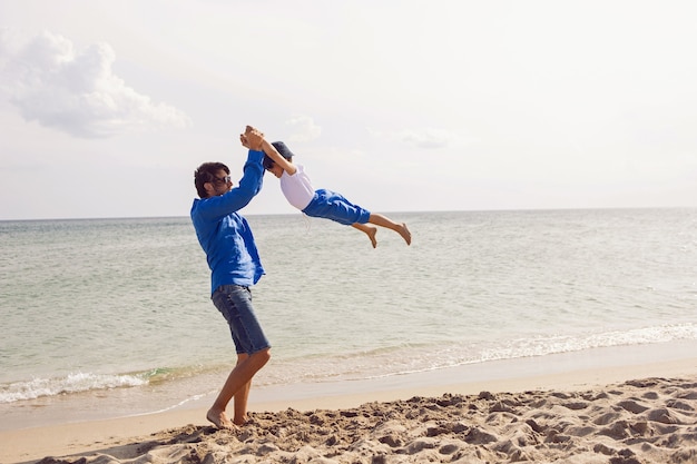 Pai e filho brincam na praia no verão com roupas azuis durante as férias