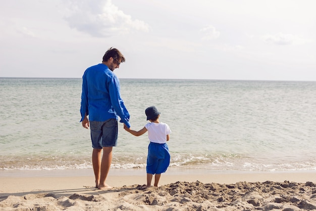 Pai e filho brincam na praia no verão com roupas azuis durante as férias