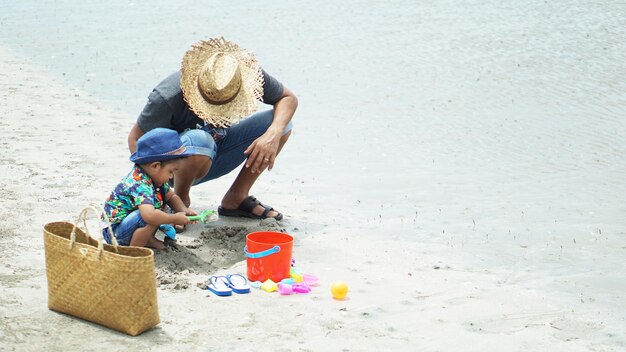 Foto pai e filho brincando com brinquedo na areia na praia