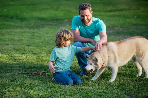 Pai e filho brincando com cachorro no jardim pai e filho com animal de estimação se divertindo ao ar livre