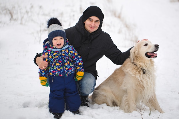 Pai e filho brincando com o cachorro na neve