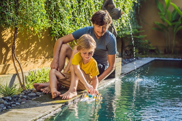 Pai e filho brincando com um barco na piscina