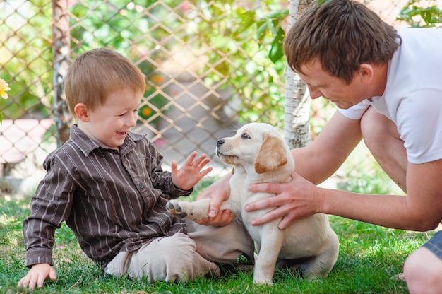 Pai e filho brincando com um filhote de cachorro Labrador