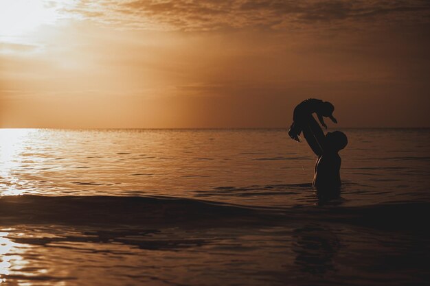 Pai e filho brincando na praia na hora do pôr do sol. Pessoas se divertindo em campo.