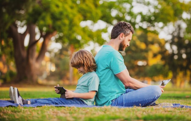 Pai e filho brincando ou estudando com laptop no parque