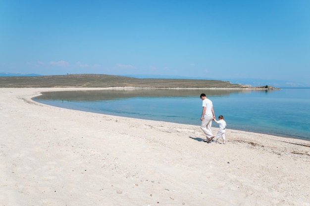 Pai e filho caminham à beira-mar