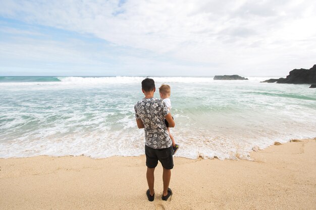 Pai e filho caminhando juntos na praia de mãos dadas