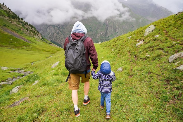 Pai e filho caminhando juntos vista das atividades de verão de longa caminhada para a família nas montanhas