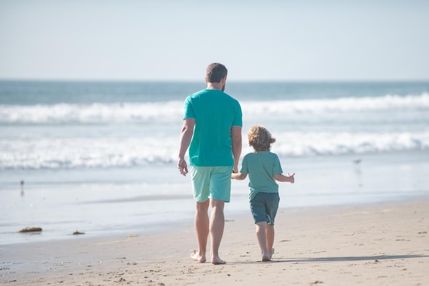 Pai e filho caminhando na praia de verão Conceito de família amigável e férias de verão
