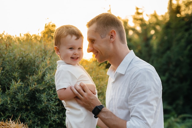 Pai e filho caminhando no parque ao pôr do sol. Felicidade. Ame